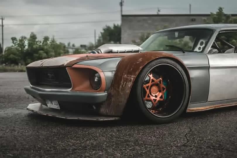 The owner's photo of their widebody Mustang, front three-quarter, with rusted panels and bare-metal doors