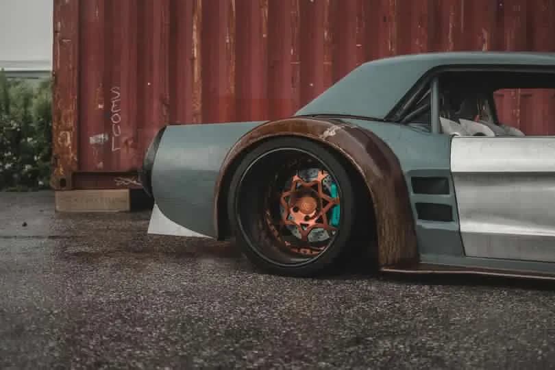 The owner's photo of the Mustang's side and wheel arch in front of a red shipping container