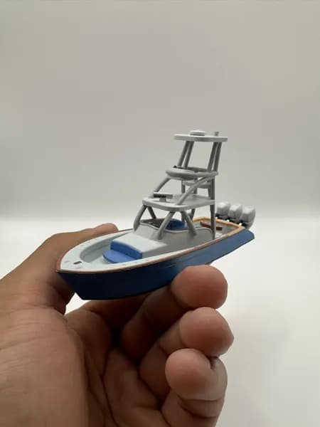 A hand holding a 3D printed sportfish boat model to show its size