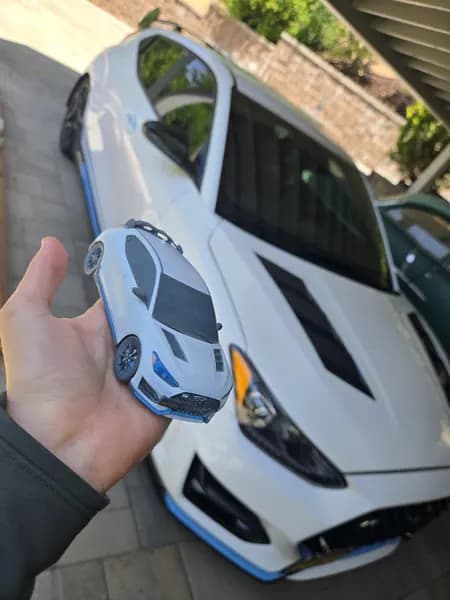 A hand holding a detailed miniature replica of a Hyundai Veloster N