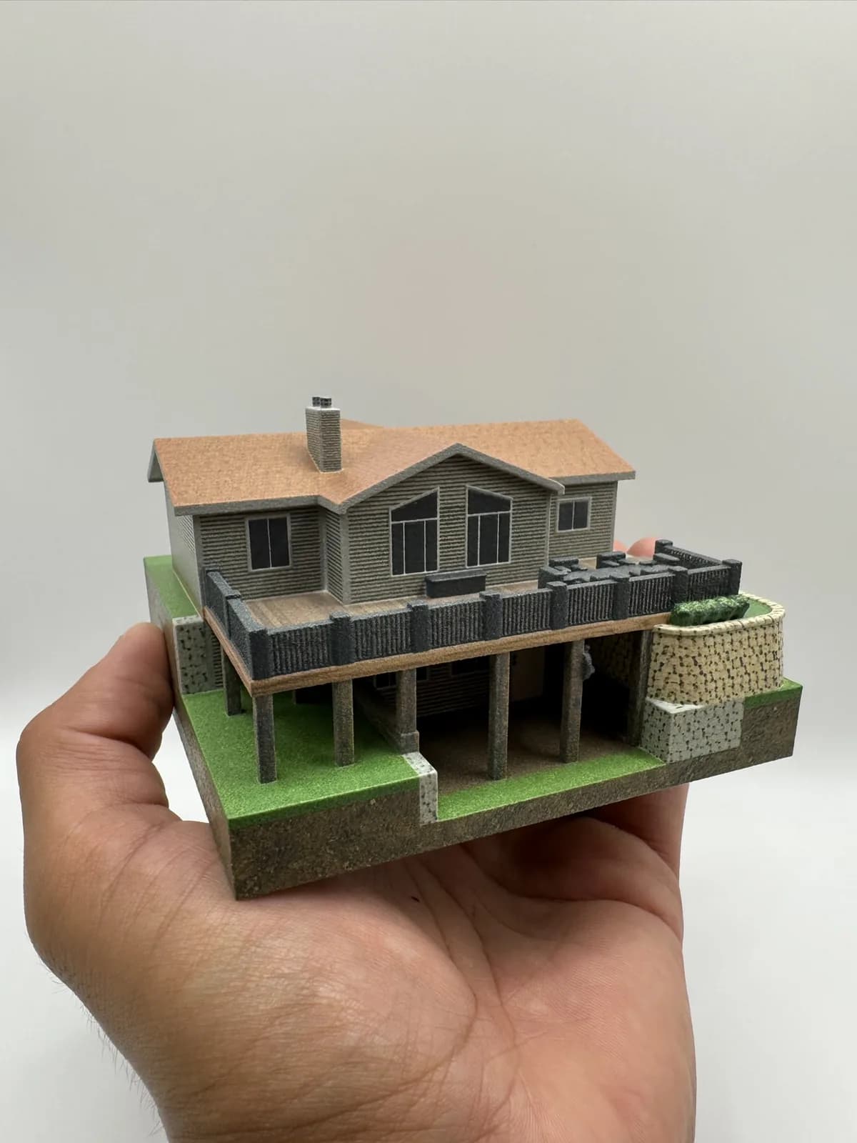 A hand holding a full-colour 3D printed model of a two-storey house