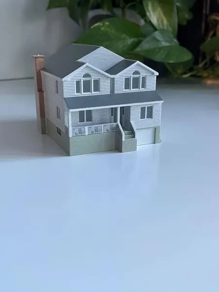 A 3D printed model of a suburban home photographed on a clean white background