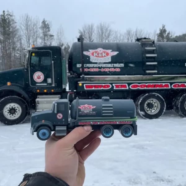 A hand holding a detailed 3D printed tanker truck model in the snow