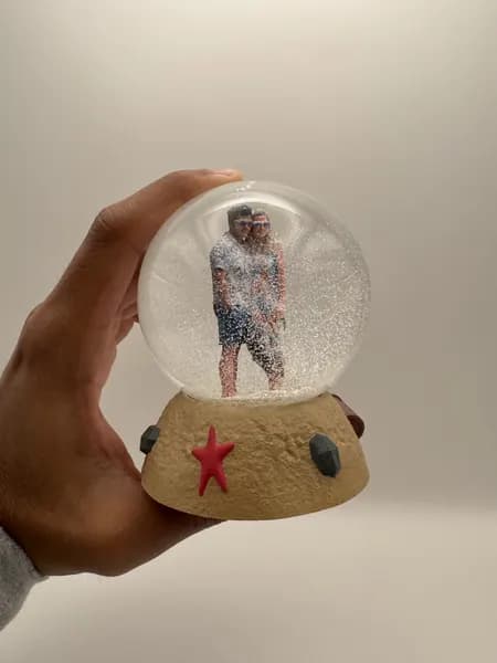 A custom 3D printed snow globe containing a couple on a hand-sculpted sand base with a starfish
