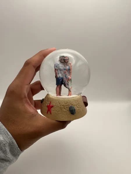 A custom 3D printed snow globe containing a couple on a hand-sculpted sand base with a starfish