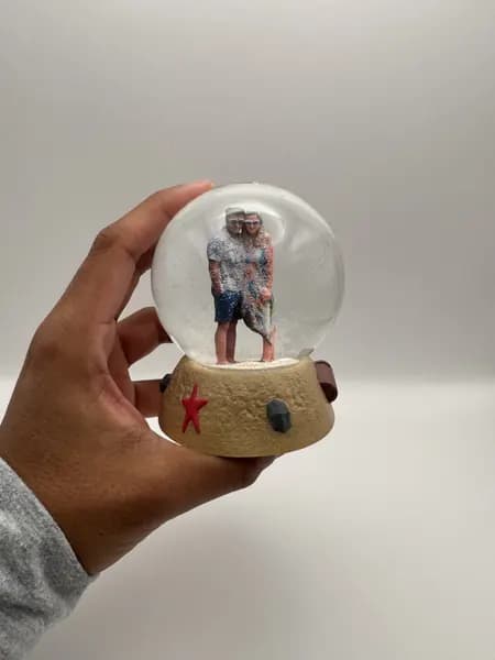 A custom 3D printed snow globe containing a couple on a hand-sculpted sand base with a starfish