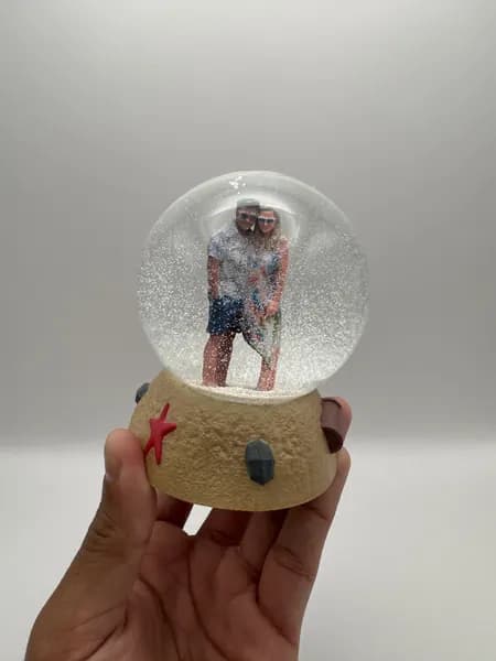 A custom 3D printed snow globe containing a couple on a hand-sculpted sand base with a starfish