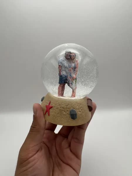 A custom 3D printed snow globe containing a couple on a hand-sculpted sand base with a starfish
