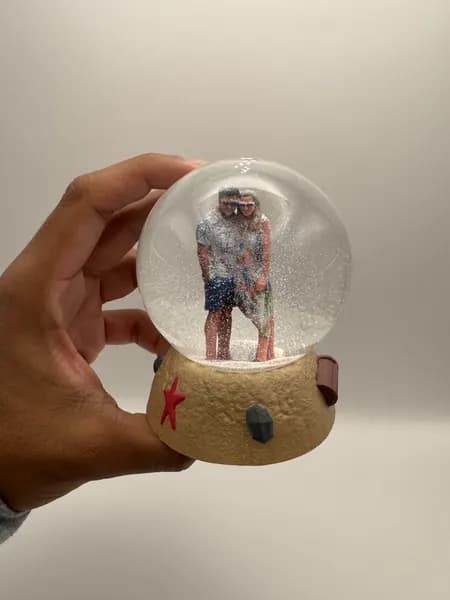 A custom 3D printed snow globe containing a couple on a hand-sculpted sand base with a starfish