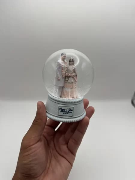 A custom 3D printed snow globe containing a couple in full Indian wedding dress