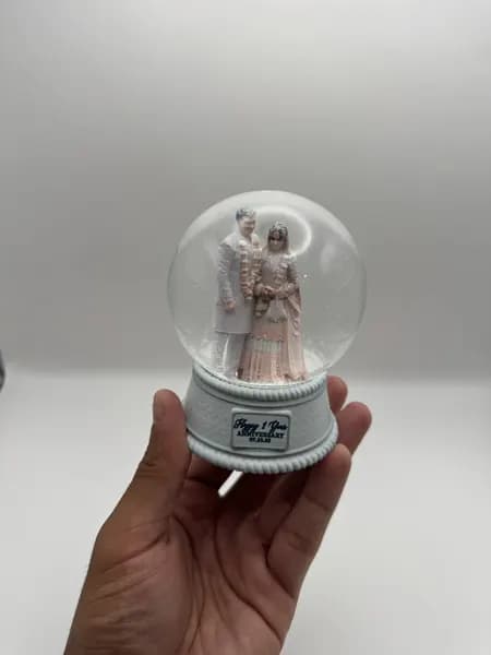 A custom 3D printed snow globe containing a couple in full Indian wedding dress