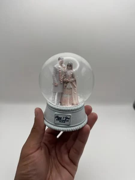 A custom 3D printed snow globe containing a couple in full Indian wedding dress