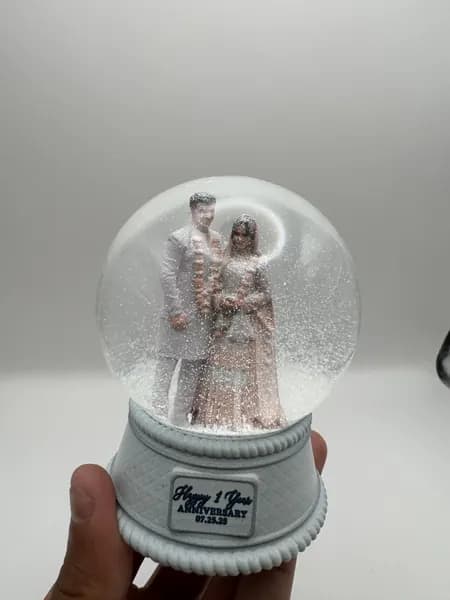 A custom 3D printed snow globe containing a couple in full Indian wedding dress