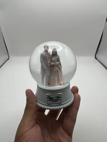 A custom 3D printed snow globe containing a couple in full Indian wedding dress