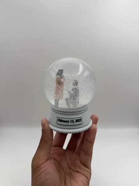 A custom 3D printed snow globe containing a proposal scene, with the date on the base
