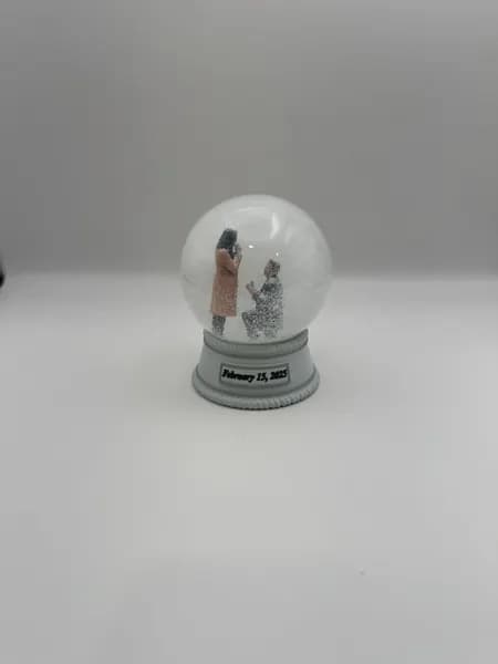 A custom 3D printed snow globe containing a proposal scene, with the date on the base